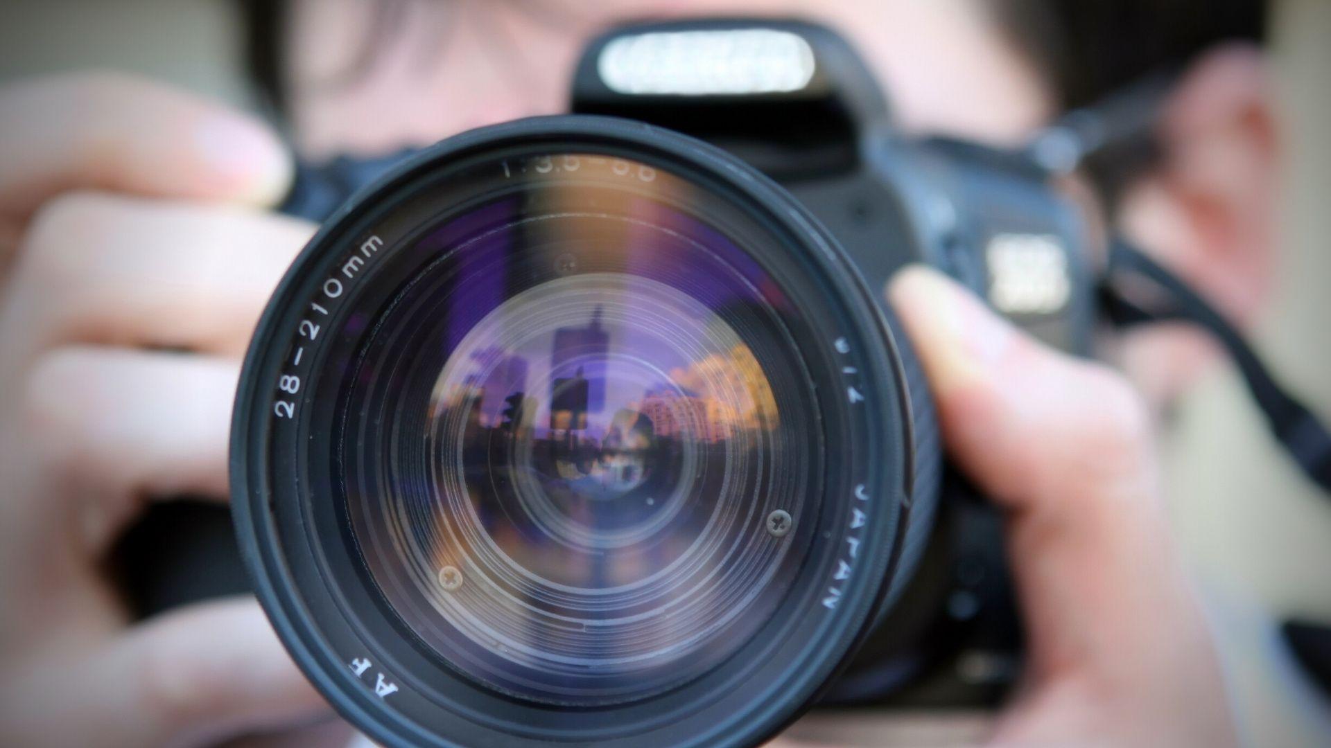 Widok obiektywu aparatu fotograficznego i mężczyzny robiącego zdjęcie.