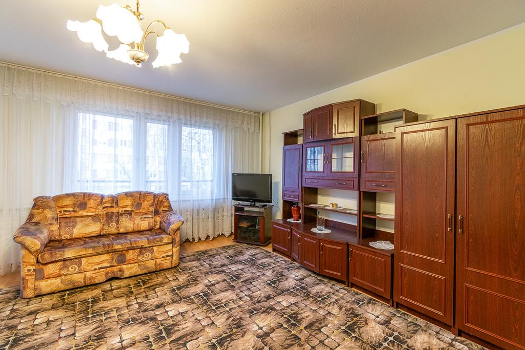 Widok na okno dużego pokoju mieszkania na sprzedaż w Pabianicach, po prawej meblościanka, na wprost sofa.